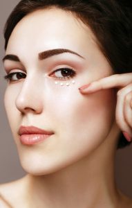 Portrait of young woman with moisturizing cream under her eye